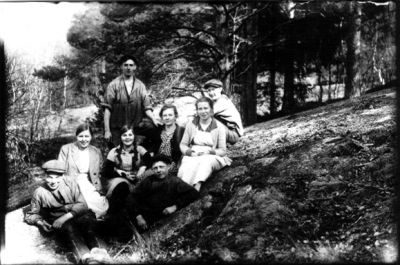 3 män och 4 kvinnor sittande på berg. Man stående.
Nyckelord: Skogsbacke