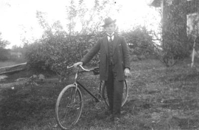 Man stående med cykel i trädgård.
Nyckelord: Cykel Bostad