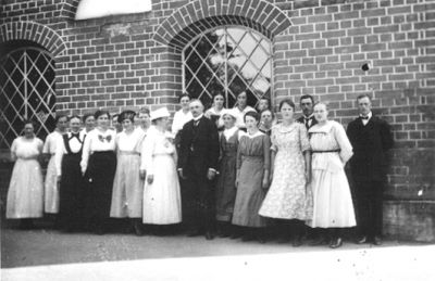 Ett antal personer stående vid kyrkvägg.
