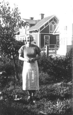 Kvinna stående i trädgård.
Nyckelord: Trädgård Grind