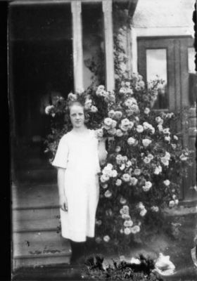 Flicka stående vid blommor framför byggnad.
Nyckelord: Blommor Trappa Bostad