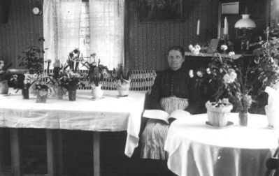 Kvinna sittande i rum med blommor.
Nyckelord: Blommor Lampa