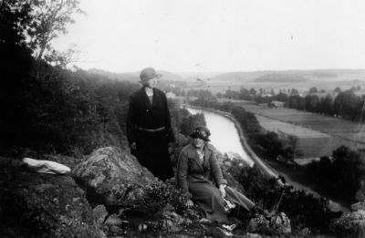 1 kvinna sittande och 1 kvinna stående på berg med vattendrag i bakgrunden.
Nyckelord: Utsikt