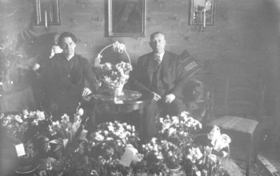 Man och kvinna sittande i rum med blommor.
Nyckelord: Blommor Tavla