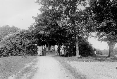 5 män 2 kvinnor 4 barn i trädgård framför byggnad
Nyckelord: Cykel