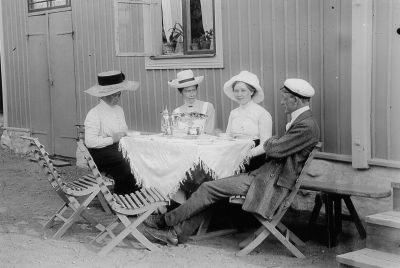 Man och 3 kvinnor i trädgårdsmöbel framför byggnad
Nyckelord: Trädgårdsmöbel Ljugarbänk Studentmössa Dräkt Hatt