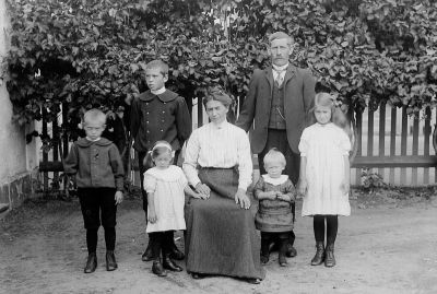 Man kvinna och 5 barn på gårdsplan
