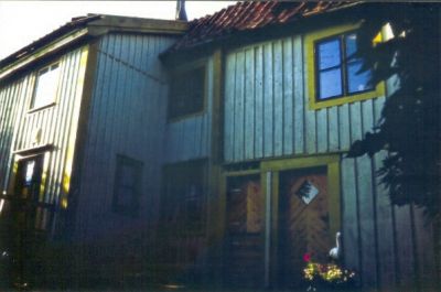 Grått trähus med gula fönsterbräder
