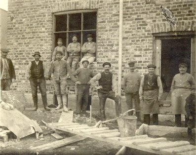 Arbetsstyrka framför tegelbyggnad
