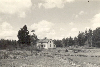 Vitt torp i skogsbryn
