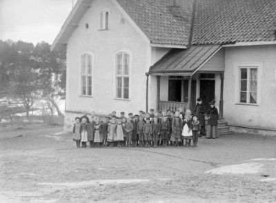 Elever och lärare framför byggnad
