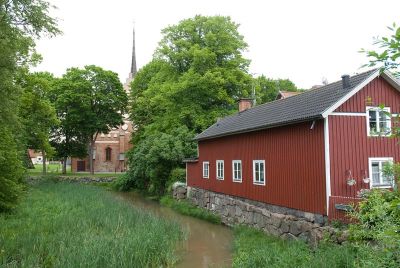 Röd träbyggnad utmed vattendrag
